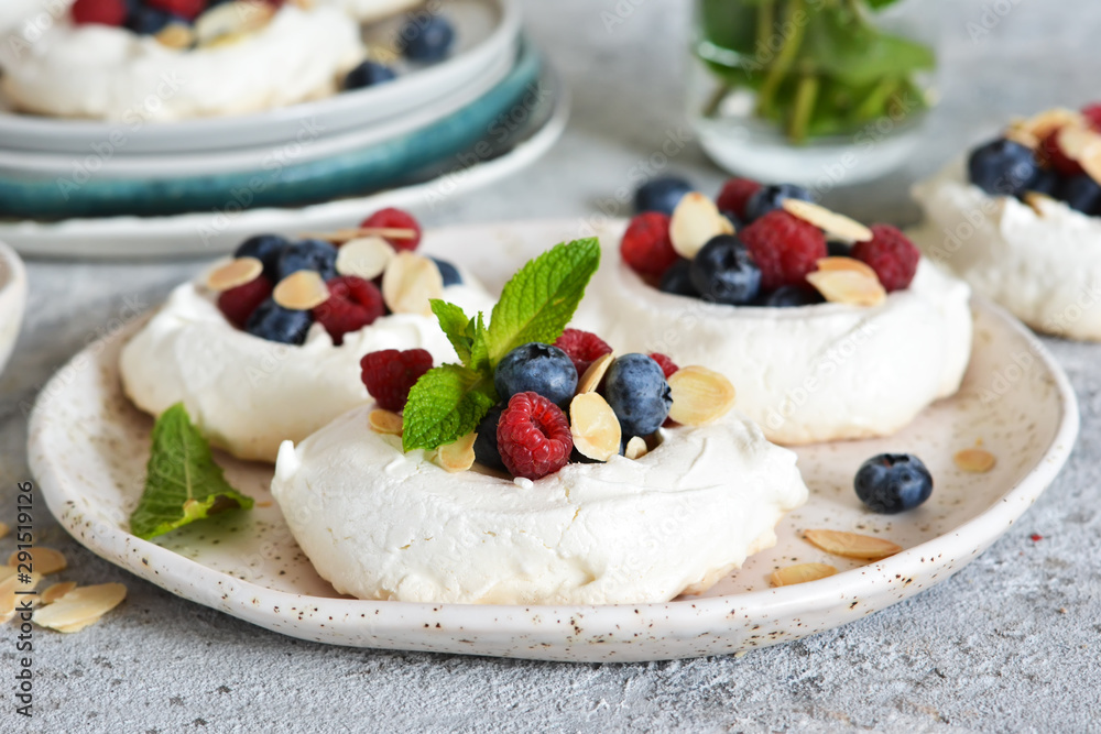 Classic dessert pavlova with cream and berries and almonds on the kitchen table. Portion dessert pavlova. Classic dessert pavlova with cream and berries and almonds on the kitchen table. Portion dessert pavlova.