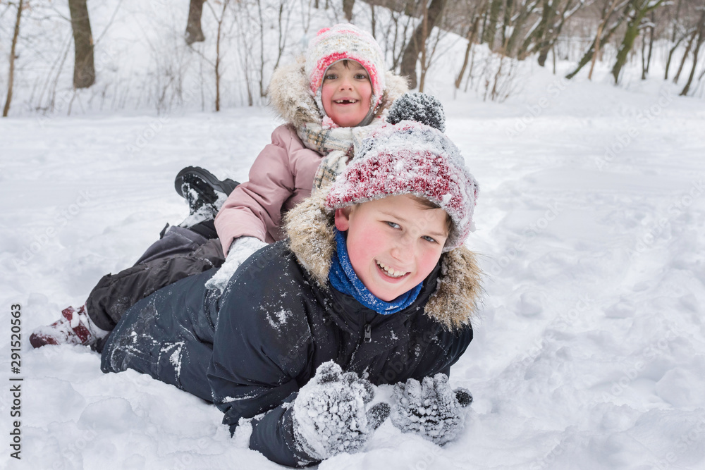 Happy children have fun playing in a snowdrift outdoors in winter.