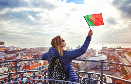 Young woman tourist enjoying beautiful cityscape top view on the old town holding the flag of Portugal in hands during the sunny day in Lisbon city photo