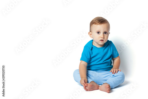 Cute baby boy sitting isolated on the white background. Copy place. Surprised and curious look of the baby will draw attention to information.