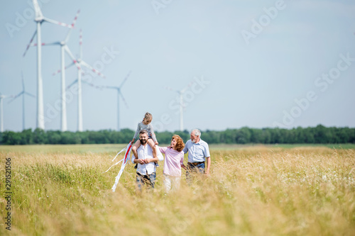 Multigeneration family walking on field on wind farm.