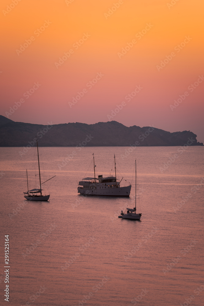 Boats seeing the sunset at August in Cavalleria beach at the north coast of Menorca, Spain.