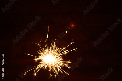 Holiday Bengal lights on the dark background. Burning sparkler  Happy New Year.