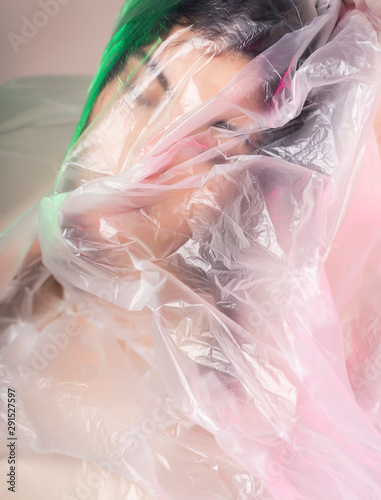 Beautiful plus size body positive brunette girl model wearing comfortable underwear sensually posing poses as if the cellophane film does not allow her to breathe. Fashionable, modern design.