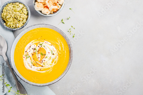 Pumpkin soup with cream, croutons, pumpkin seeds and thyme on a gray concrete or stone background Top view Flat lay Copy space