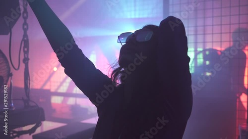 Dancing young woman with a drink in a hand silhouette at techno club photo