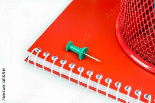 Fragment of a red notebook with a green button isolated on a white background.
