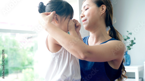 Asian Mother comforting her daughter from a minor injury during the morning yoga practicing session