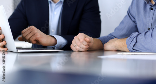 Business people using tablet computer while working together at the desk in modern office. Headshot of businessman or male entrepreneur with colleague at workplace. Teamwork and partnership concept
