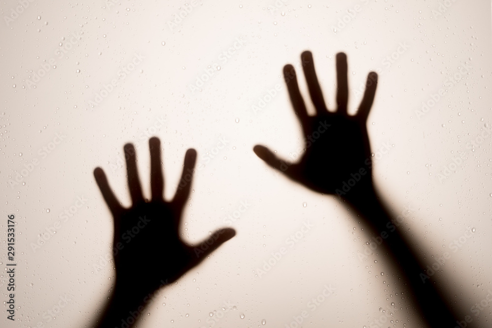 Scared person's Arms Silhouette behind frosted window, beating on window and trying to get out. Ghost like figure. Scared person's Arms Silhouette behind frosted window, beating on window and trying to get out. Ghost like figure.