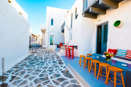 Beautiful sitting place with light brown wooden chairs and colorful pillows on the courtyard of greek street