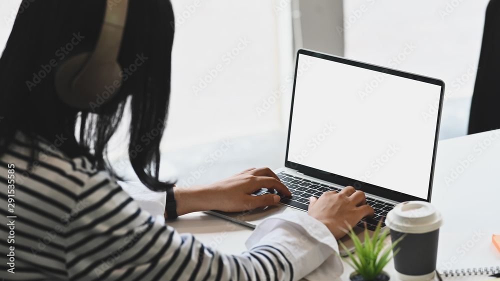 Young woman wearing headphones and using isolated white screen of laptop computer. Young woman wearing headphones and using isolated white screen of laptop computer.