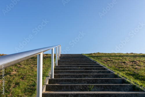 minimal background with a staircase  green grass field  and clear blue sky.
