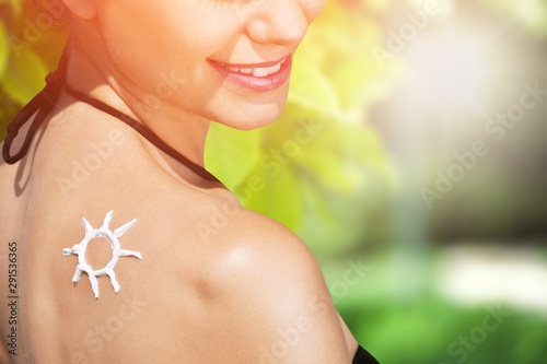 Young woman with sun drawn with cream on shoulder