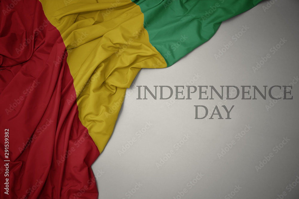 waving colorful national flag of guinea on a gray background with text independence day.