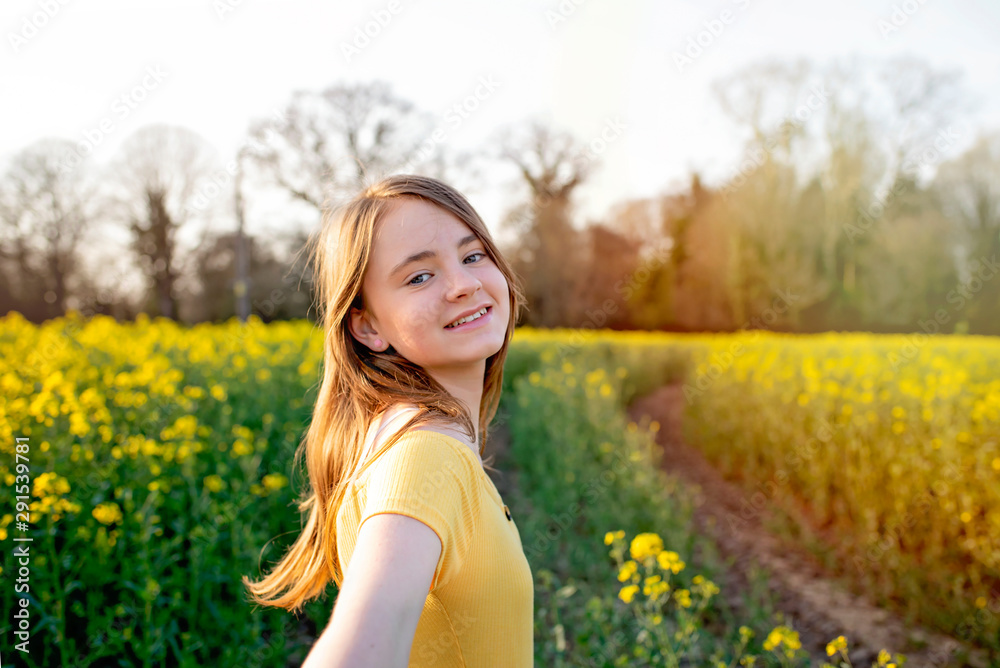 Young girl walking through yellow and green spring countryside fields Young girl walking through yellow and green spring countryside fields