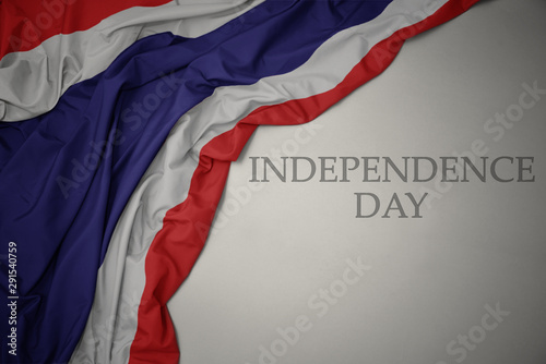 waving colorful national flag of thailand on a gray background with text independence day.