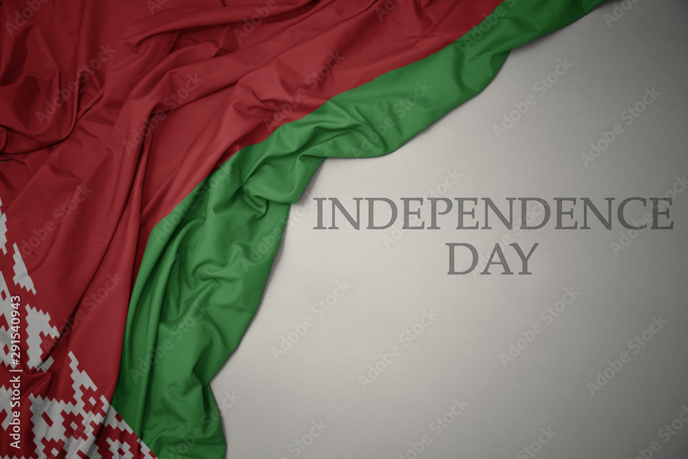 waving colorful national flag of belarus on a gray background with text independence day.