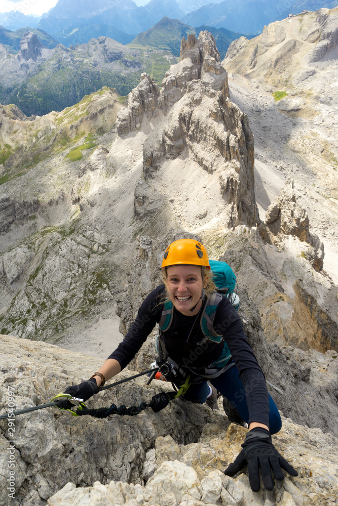attractive female climber on a steep Via Ferrata in the Italian Dolomites