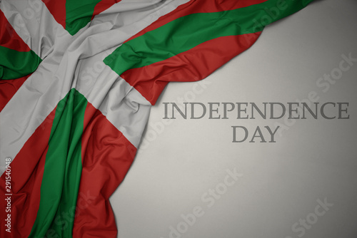 waving colorful national flag of basque country on a gray background with text independence day.