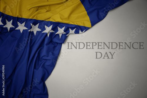 waving colorful national flag of bosnia and herzegovina on a gray background with text independence day.