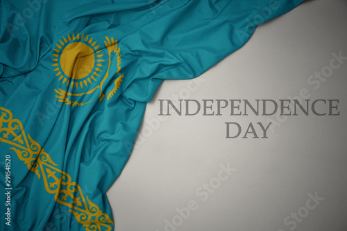 waving colorful national flag of kazakhstan on a gray background with text independence day.