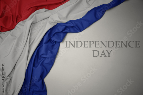 waving colorful national flag of netherlands on a gray background with text independence day.