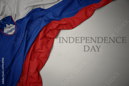 waving colorful national flag of slovenia on a gray background with text independence day.