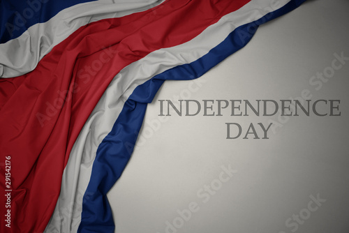 waving colorful national flag of costa rica on a gray background with text independence day.