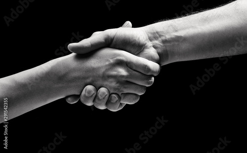 Concept of salvation. Image of the hands of two people at the time of rescue on black isolated background. Black and white image.