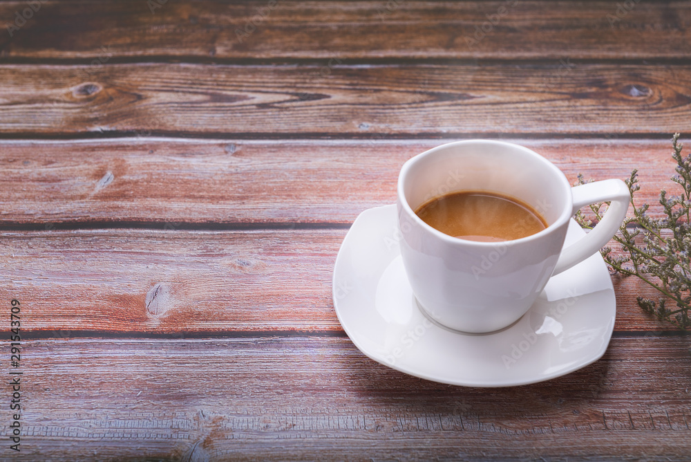 Hot coffee in a white glass on the old wooden floor on the side with flowers ,copy the area for the text Hot coffee in a white glass on the old wooden floor on the side with flowers ,copy the area for the text