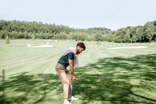 Man playing golf, swinging with putter on a beautiful course on a sunny day