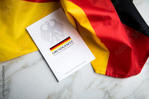 Das Grundgesetz Buch der Bundesrepublik Deutschland auf Flagge und Marmor Hintergrund