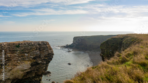 Coastline view taken at the Souter Lighthouse in South Shields, Tyne and Wear, England UK. Sunny day with warm blue sky, clouds and calm North Sea. © Anthony