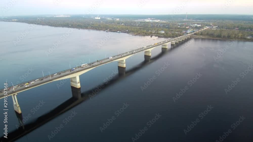 Aerial view of a long bridge over a wide river, active traffic on the bridge.the bridge is reflected in the water.4k.Copy space Aerial view of a long bridge over a wide river, active traffic on the bridge.the bridge is reflected in the water.4k.Copy space