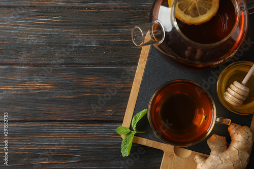Cup of tea, mint, honey, ginger and teapot on wooden background, top view