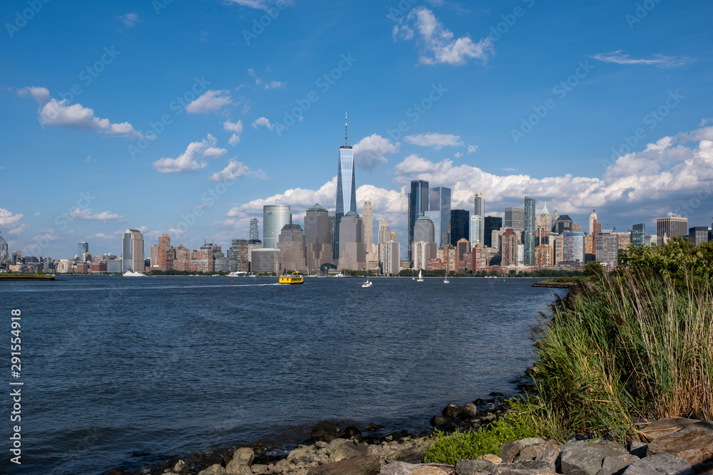 Lower Manhattan skyline with boat and ferry on Hudson river view from Liberty State Park in late summer