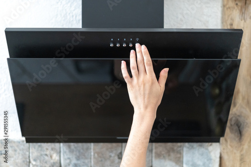 Картината върху платно Woman select program at modern extractor hood