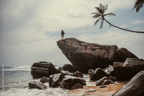 Men is standing on the large rock enjoying the ocean's view