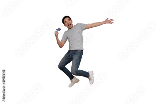 Excited Asian young man in gray t-shirt jumping and holding credit card isolated over white background, Full length portrait concept