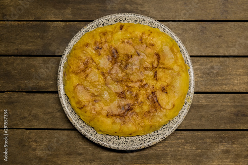 vegan Spanish omelette with potatoes onion and garlic, isolated in a wooden table