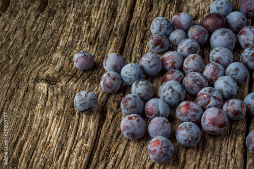 Ripe blue plums (cherry plum) on a dark wooden ruskic background. Top view or flat lay.