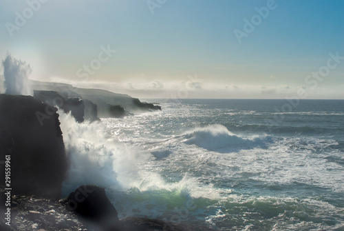 Summertime, Atlantic ocean, waves crashing against rocks, blue sky, turquoise water, drama on the the west coast of Ireland.