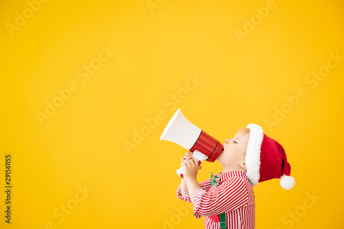 Happy child wearing Santa Claus costume speaking by megaphone