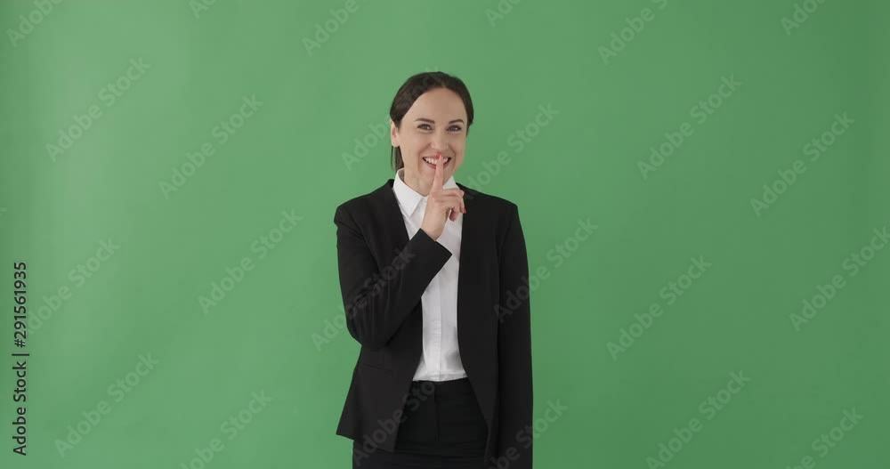 Excited businesswoman with finger on lips over green background Excited businesswoman with finger on lips over green background