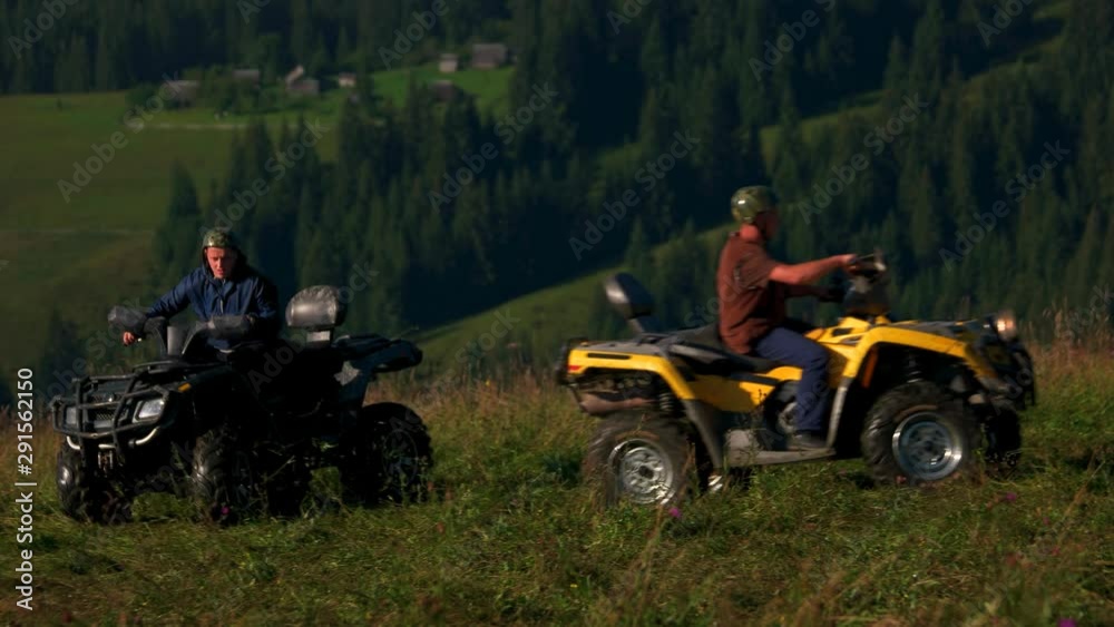 Quad bikes riding in mountain. Men riding quad bikes on grassy mountain hills. Outdoors summer activity. Quad bikes riding in mountain. Men riding quad bikes on grassy mountain hills. Outdoors summer activity.