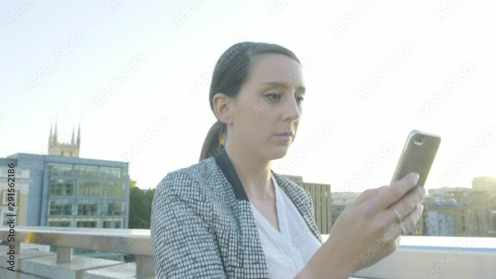 Steady cam view of an attractive caucasian business woman commuter walking using smartphone on London bridge at sunset Steady cam view of an attractive caucasian business woman commuter walking using smartphone on London bridge at sunset