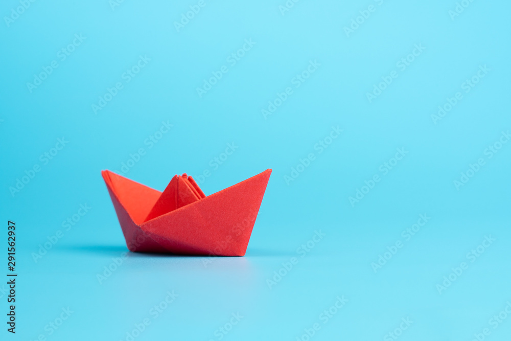 Obraz premium Origami red paper boat on blue background