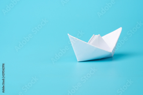 Origami white paper boat on blue background
