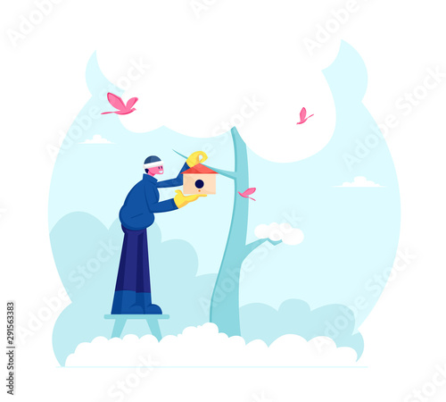Man Hanging Birdhouse on Tree in Winter or Spring Time